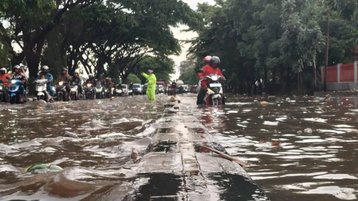 Petugas kepolisian tengah mengatur laju kendaraan melintasi area banjir di Jalan Soekarno Hatta, Gedebage, Kota Bandung. (Dok. Jabar Ekspres)