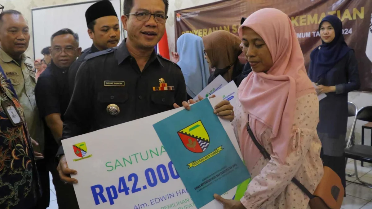 Bupati Bandung, Dadang Supriatna (kiri) saat berikan santunan secara simbolis kepada ahli waris alias Mellya Danius (kanan), istri almarhum Edwin Hadyana (53), Ketua KPPS di Cileunyi Bandung yang Meninggal Usai Pemilu 2024. (Istimewa)