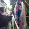 Ibu Kokom saat menjemur pakaian milik warga. Foto : Sandika Fadilah/jabareskpres.com