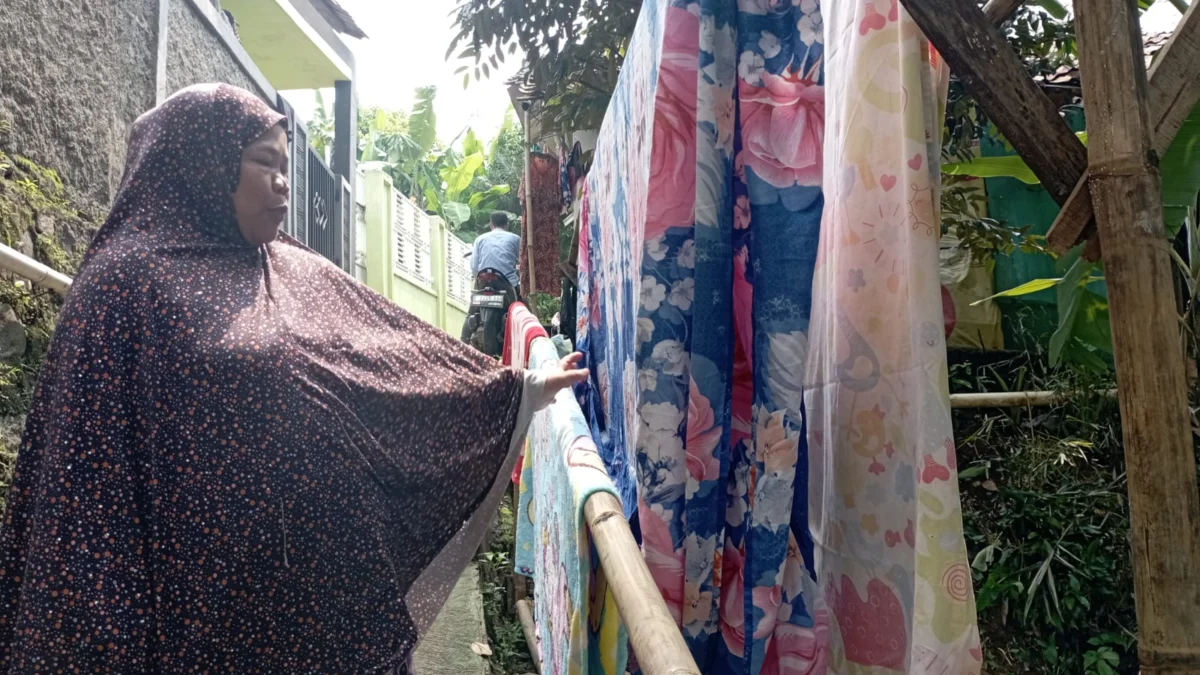 Ibu Kokom saat menjemur pakaian milik warga. Foto : Sandika Fadilah/jabareskpres.com