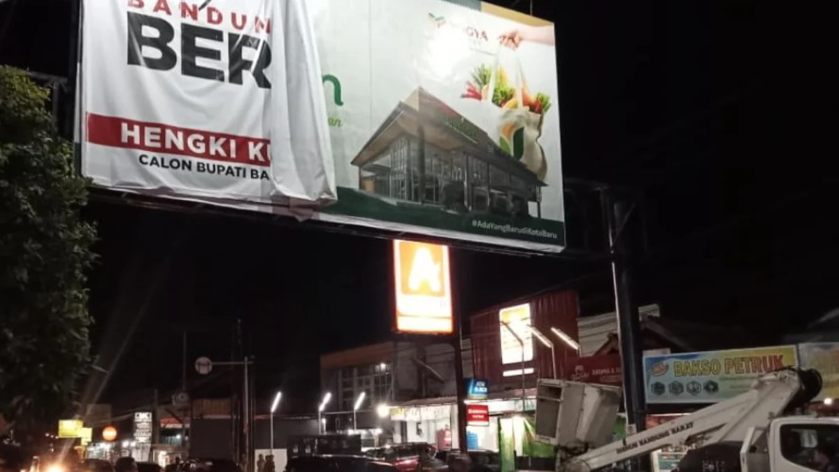 Petugas Satpol PP KBB saat menertibkan baliho mantan Bupati Bandung Barat, Hengky Kurniawan yang terpasang di ppan reklame di ruas Jalan Raya Cimareme, KBB.