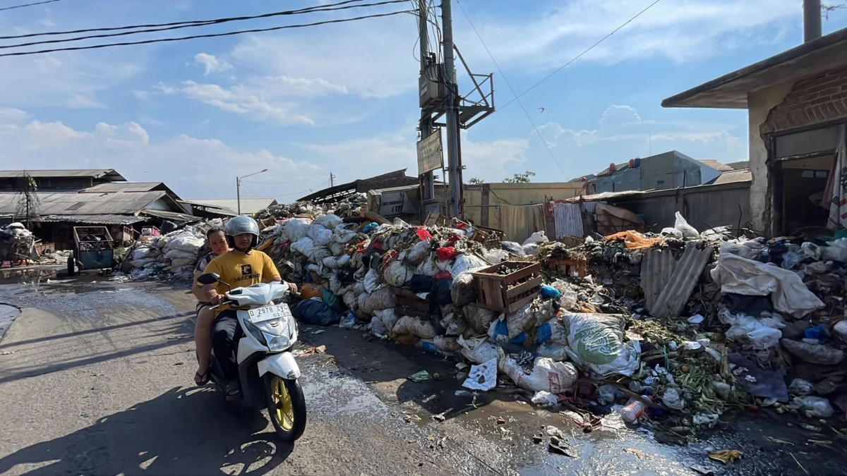 Masyarakat saat melintas tumpukan sampah yang berada di belakang Pasar Baleendah, Kabupaten Bandung, Kamis (18/4/2024). Foto Agi Jabar Ekspres