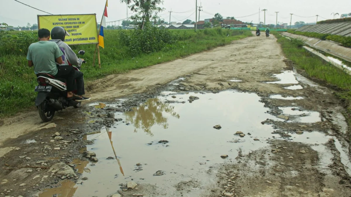 Masyarakat melintasi jalanan rusak di kawasan Desa Cibiru Hilir, Kecamatan Cileunyi, Kabupaten Bandung. (Pandu Muslim/Jabar Ekspres)