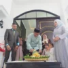 Kepala Dinas Pendidikan dan Kebudayaan Kota Banjar, H Kaswad disaksikan pengusaha buah Thomas Ardiansyah dan istri Rina, memotong nasi tumpeng, Minggu 5 Mei 2024. (Cecep Herdi/Jabar Ekspres)