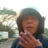 Pengendara motor yang merokok ditengah jalan hingga abu rokoknya mengenai pengendara lain. Foto tangkapan layar.