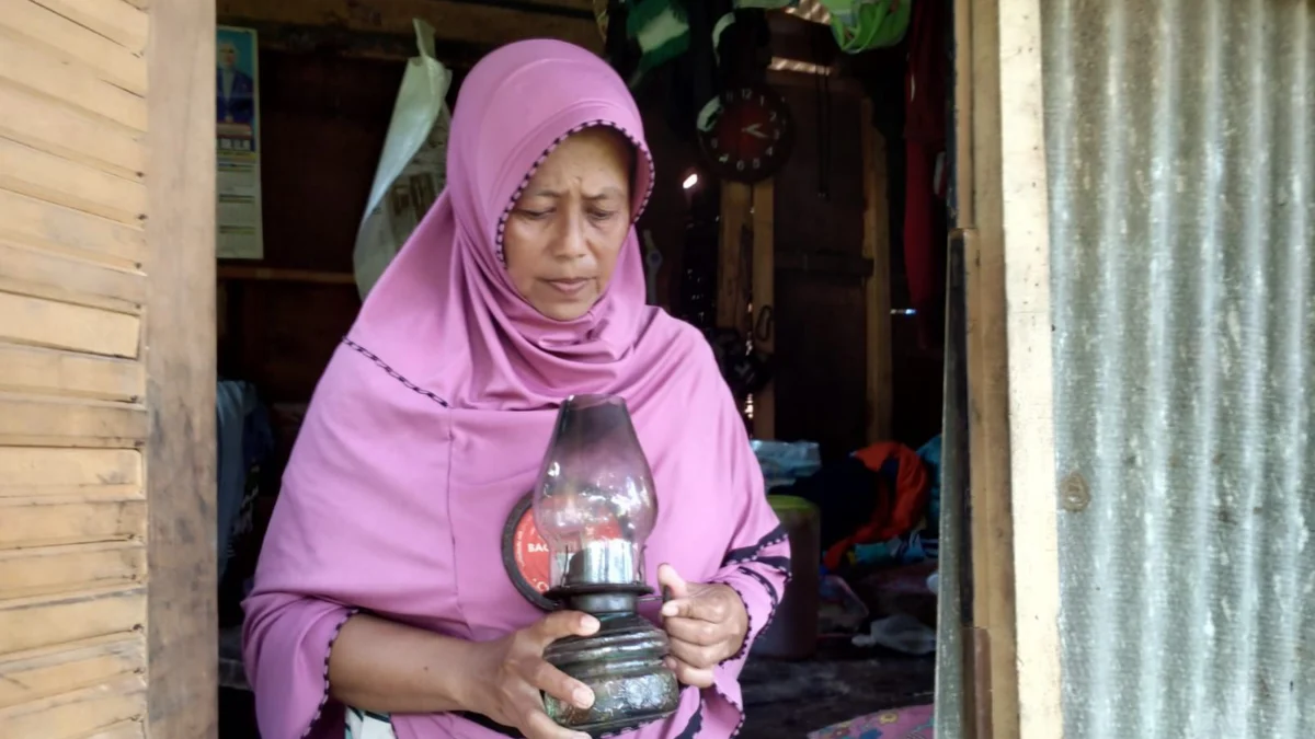 Herlina, istri Engkus berdiri memegang cempor di depan gubuk reyot di pinggiran hutan Kota Banjar, baru-baru ini. (Cecep Herdi/Jabar Ekspres)
