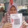 Pedagang di Pasar Cigombong saat menunjukan barcode pembayaran dengan QRIS. Foto : Istimewa