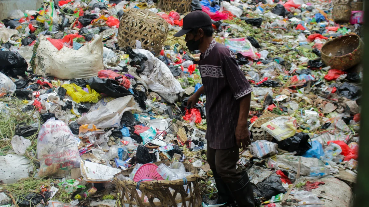 Pengelolaan Sampah Komersil, Pemerintah Minta Kelola Mandiri Tapi Tagih Retribusi Tinggi Ilustrasi: Seorang pria tengah berada di atas tumpukan sampah Pasar Sehat Cileunyi, Kabupaten Bandung. (DOK: Jabar Ekspres)