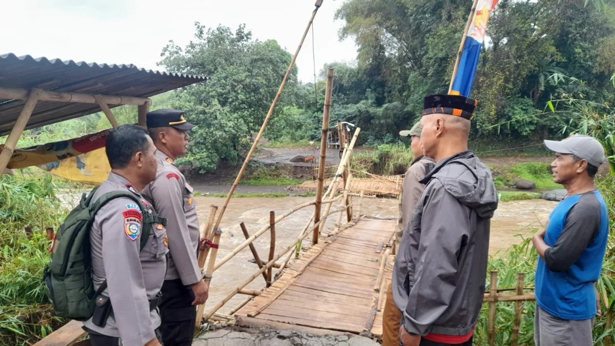 Imbas Meluapnya Aliran Sungai, Jembatan Kayu Penghubung Dua Desa Terputus PIhak kepolisian saat mengecek kondisi jembatan yang menghubungkan dua desa Pacet dan Majalaya terputus akibat derasnya debit air anak sungai citarum. Foto Istimewa