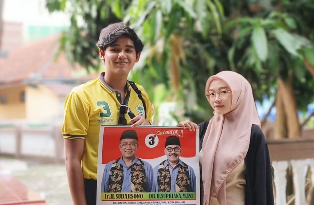 Janji Masagi, Bakal Aktifkan Lagi Tunjangan Daerah Guru ASN Banjar Dua muda-mudi memegang gambar berisikan pasangan calon Walo Kota dan Wakil Walikota Banjar nomor urut 3, Sudarsono dan Supriana. Paslon ini menjanjikan Tunjangan Daerah (Tunda) ASN Guru diberikan lagi. (Foto:Istimewa)