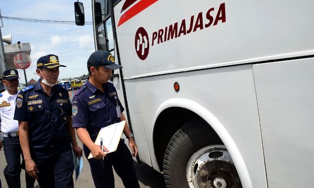 Dua orang petugas sedang melakukan pengecekan kepada kendaraan umum jelang libur Nataru