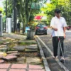 TUNANETRA: Seorang penyandang disabilitas tunanetra saat menggunakan bahu jalan, lantaran trotoar rusak dan membahayakan di Kota Bandung. (Ilustrasi/Jabar Ekspres)