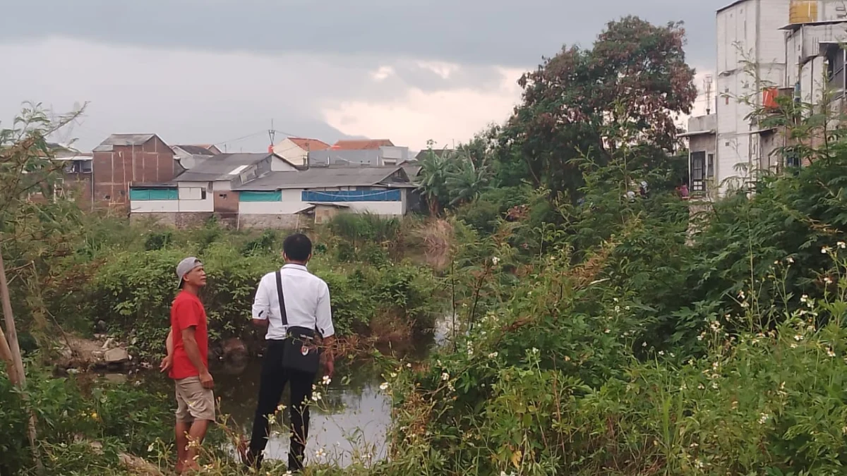 Kesaksian Warga: Sebelum Ditemukan Tak Bernyawa, Korban Terlihat Bermain Air di Sungai Cimande Rancaekek Bandung Ading (46), warga RT01 RW04, Kampung Kekencehan, Desa Cangkuang, Kecamatan Rancaekek (baju merah) sedang memberikan kesaksiannya ke pihak Polisi saat olah TKP penemuan jenazah pria tanpa identitas di Sungai Cimande. (Yanuar/Jabar Ekspres)