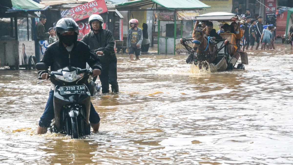 Warga melintasi banjir yang menggenangi jalan raya Dayeuhkolot - Banjaran di Kabupaten Bandung, Sabtu (25/1). Foto: Dimas Rachmatsyah / Jabar Ekspres
