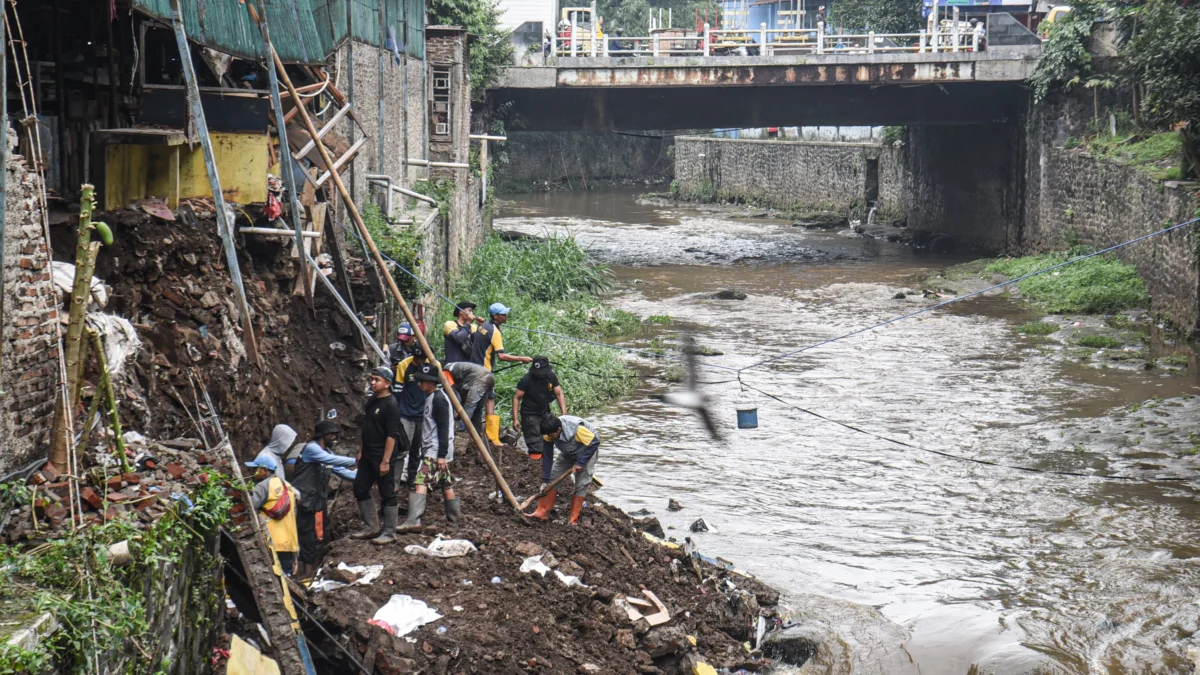 Petugas memperbaiki tanggul dan tembok bangunan yang jebol di Pasar Ancol, Kota Bandung, Selasa (25/2). Foto: Dimas Rachmatsyah / Jabar Ekspres