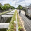 Seorang warga berjalan di samping kolam retensi Gedebage, Kota Bandung. Foto: Dimas Rachmatsyah / Jabar Ekspres
