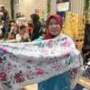 Salah satu karyawan Zahra Sulaman menunjukkan salah satu produk kain sulaman khas Bukittinggi untuk bahan kebaya di Inacraft 2025