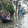 Seorang warga tengah menaiki perahu di saat banjir.