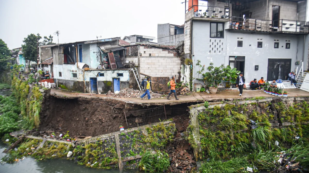 Petugas BPBD berjalan diatas jalan yang amblas di pinggir sungai Cikapundung Kolot, Jalan H Basuki, Kelurahan Binong, Kota Bandung, Rabu (26/2).