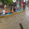 Warga saat melintasi Jalan Raya Dayeuhkolot menggunakan perahu lantaran ketinggian air mencapat satu meter lebih. Foto Agi