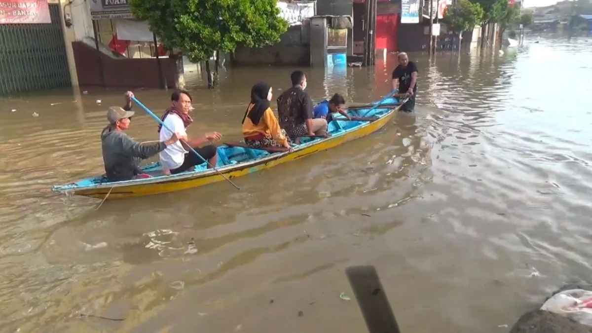 Warga saat melintasi Jalan Raya Dayeuhkolot menggunakan perahu lantaran ketinggian air mencapat satu meter lebih. Foto Agi
