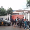 Sejumlah warga berada di depan pabrik dan satu unit mobil Reskrim Polres Sumedang tengah memasuki area PT Adira Semesta Industry, untuk menyelidiki dugaan tiga pekerja yang diduga meninggal saat membersihkan sumur limbah. (Yanuar/Jabar Ekspres)