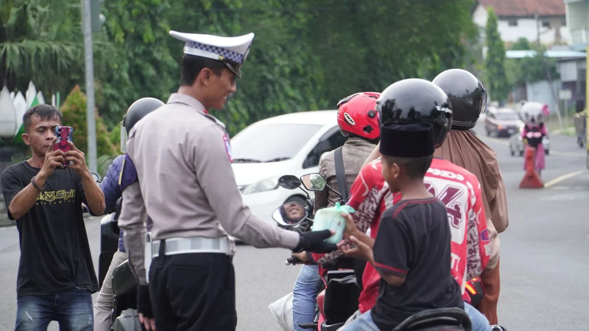 Salah satu anggota Satlantas Polres Banjar saat memberikan takjil kepada salah satu pengendara bermotor di jalan raya kota Banjar, Rabu (5/3/3025).