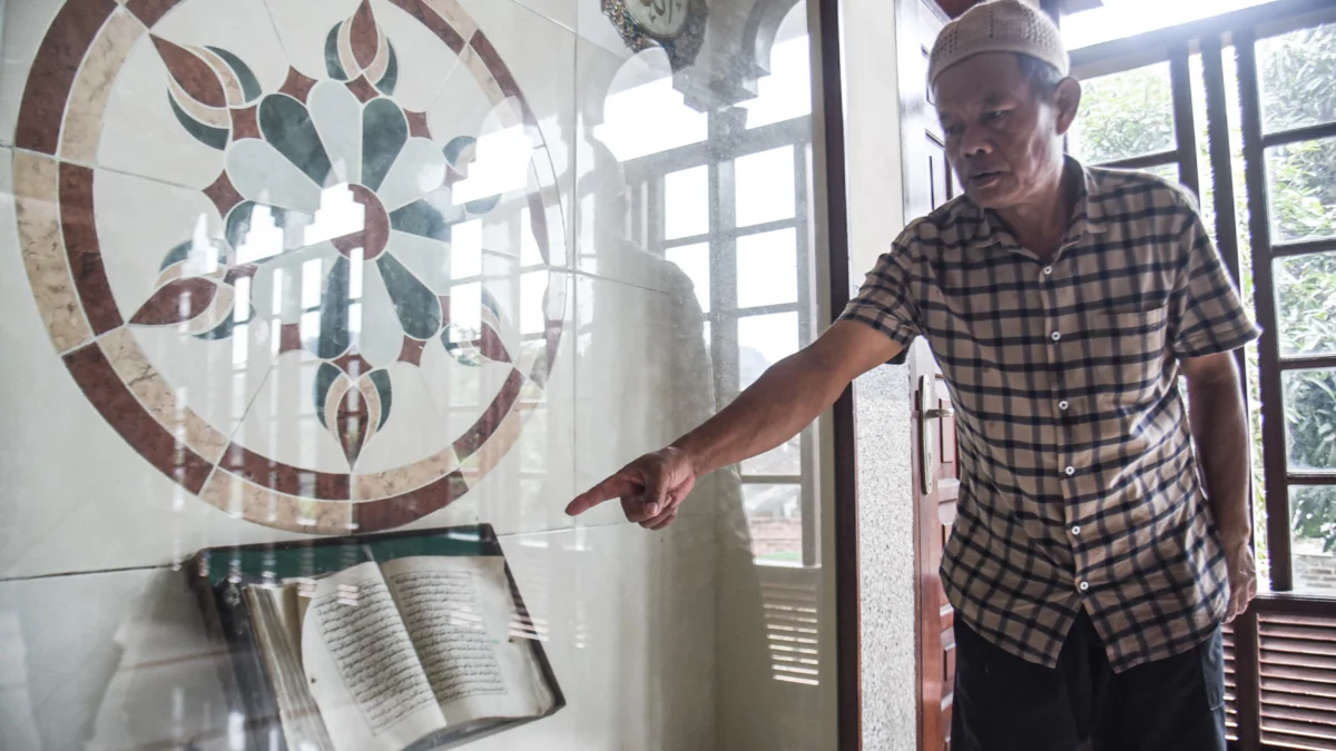 Didin (57) Penjaga masjid menunjukkan kitab suci Al Quran tertua sekitar tahun 1960an yang dibuat menggunakan tulisan tangan di Masjid Mungsolkanas, Jalan Cihampelas, Kota Bandung. Foto: Dimas Rachmatsyah / Jabar Ekspres