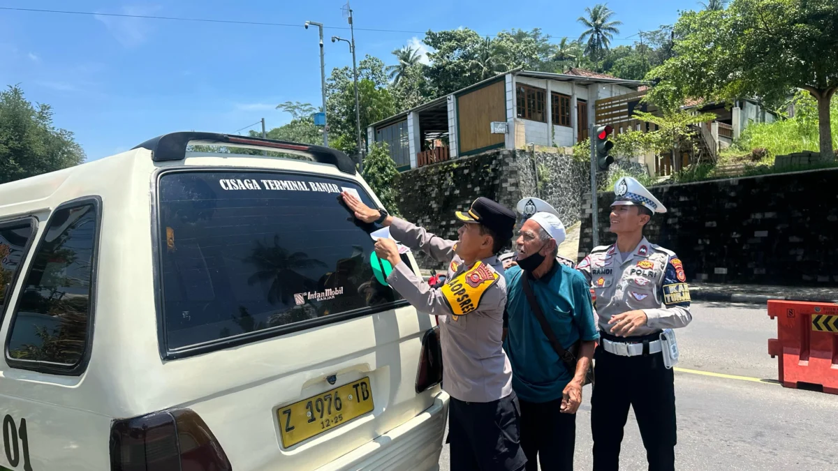 Waka Polres Banjar Kompol Dani Prasetya memasang stiker di kaca belakang angkutan kota, Kamis (13/3/2025). (Cecep Herdi/Jabar Ekspres)