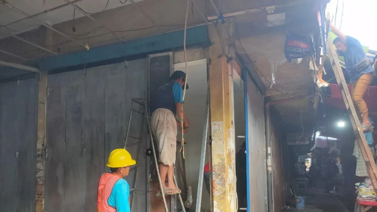 Pekerja sedang memperbaiki pintu besi yang sempat terkena api untuk bisa difungsikan kembali, Kamis (13/3/2025). (Fatkhur Rizqi/Radar Tasikmalaya)