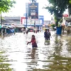 Warga melintasi genangan air banjir di Jalan Raya Dayeuhkolot, Kabupaten Bandung, Minggu (16/3). Foto: Dimas Rachmatsyah / Jabar Ekspres