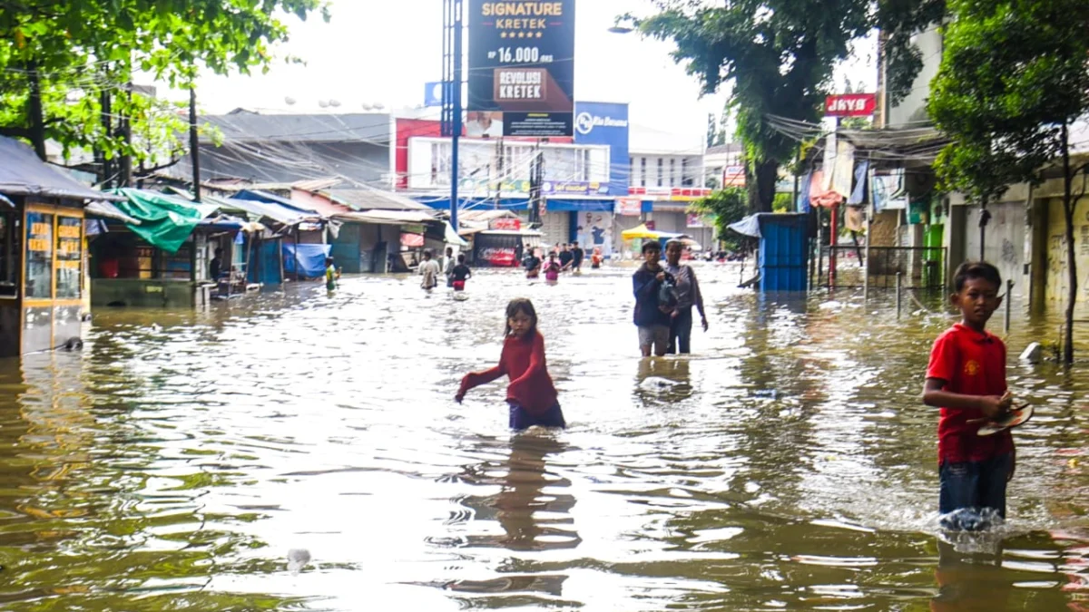 Warga melintasi genangan air banjir di Jalan Raya Dayeuhkolot, Kabupaten Bandung, Minggu (16/3). Foto: Dimas Rachmatsyah / Jabar Ekspres