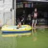 Seorang anak bermain di depan rumahnya yang terendam banjir di Kampung Cijagra, Bojongsoang, Kabupaten Bandung, Minggu (9/3). Foto: Dimas Rachmatsyah / Jabar Ekspres