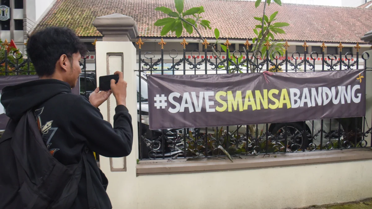 Seorang jurnalis memotret spanduk SAVESMANSABANDUNG di depan SMAN 1, Kota Bandung, Jum'at (25/4). Foto: Dimas Rachmatsyah / Jabar Ekspres