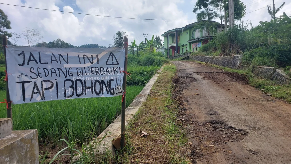 Warga memasang baliho bertuliskan sindiran kepada pemerintah lantaran dinilai lamban memperbaiki jalan yang rusak, belum lama ini. (Cecep Herdi/Jabar Ekspres)