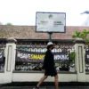 Seorang warga berjalan di samping plang tanah milik Pemerintah Provinsi Jawa Barat di SMA Negeri 1, Kota Bandung, Jum'at (18/4). Foto: Dimas Rachmatsyah / Jabar Ekspres