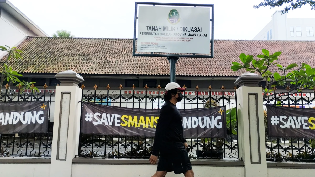 Seorang warga berjalan di samping plang tanah milik Pemerintah Provinsi Jawa Barat di SMA Negeri 1, Kota Bandung, Jum'at (18/4). Foto: Dimas Rachmatsyah / Jabar Ekspres