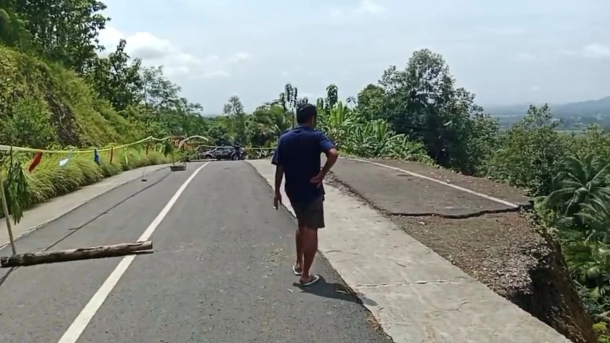 Seorang warga berada di lokasi pergeseran tanah yang menyebabkan bahu Jalan Angsana Gunung Kelir di Desa Neglasari, Kecamatan Pamarican, Kabupaten Ciamis, longsor, Minggu (20/4/2025). (Cecep Herdi/Jabar Ekspres)