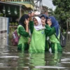 Siswi SMP melakukan swafoto saat melintasi banjir di kawasan permukiman akibat hujan yang mengguyur Bandung Raya pada Kamis (15/5) di Kampung Bojongasih, Dayeuhkolot, Kabupaten Bandung, Jumat (16/5). Foto: Dimas Rachmatsyah / Jabar Ekspres