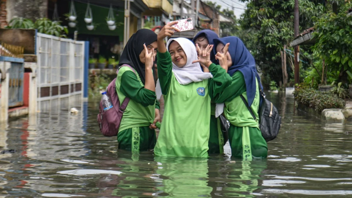 Siswi SMP melakukan swafoto saat melintasi banjir di kawasan permukiman akibat hujan yang mengguyur Bandung Raya pada Kamis (15/5) di Kampung Bojongasih, Dayeuhkolot, Kabupaten Bandung, Jumat (16/5). Foto: Dimas Rachmatsyah / Jabar Ekspres