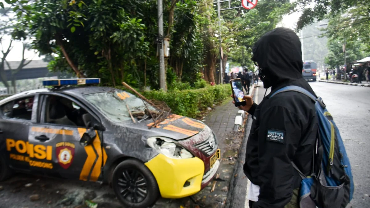 Seorang Jurnalis memotret mobil Polisi yang rusak akibat ricuh oleh orang tidak dikenal pada demonstrasi Hari Buruh Sedunia di Jalan Dipatiukur, Kota Bandung, Kamis (1/5). Foto: Dimas Rachmatsyah / Jabar Ekspres