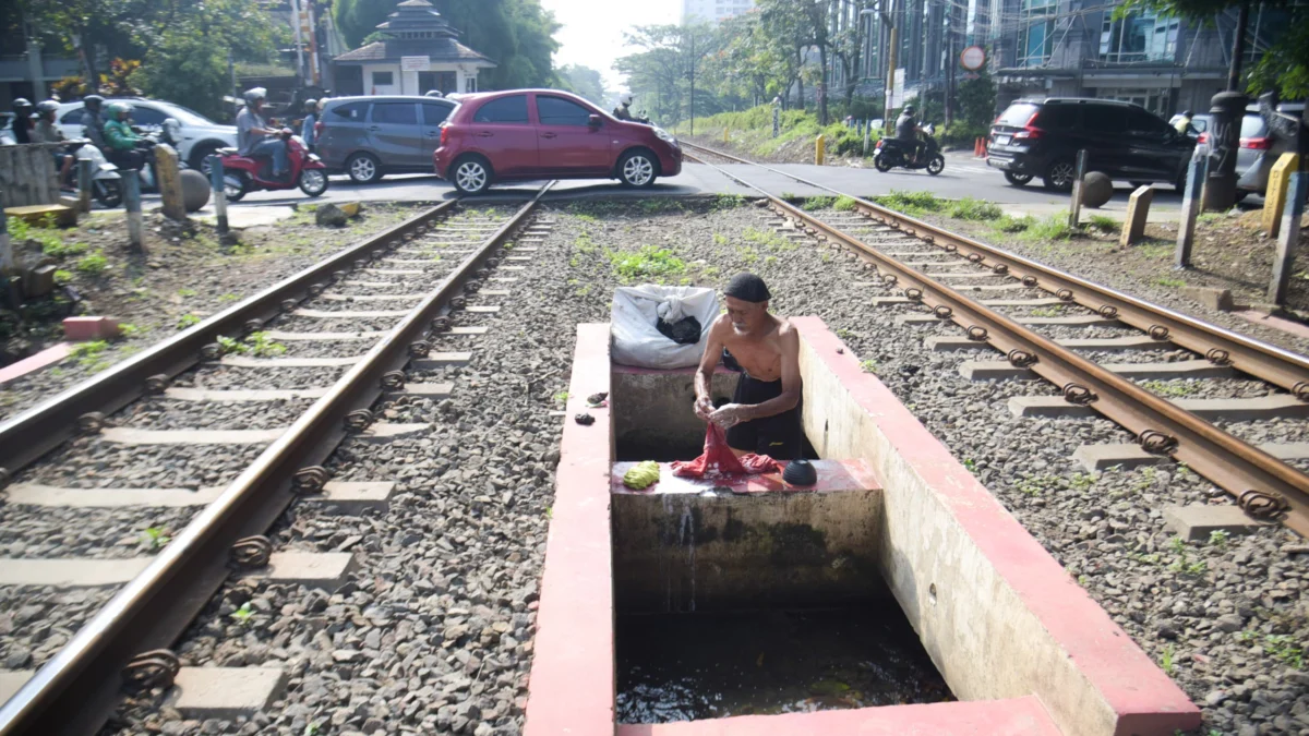 PPKS Asal Luar Kota Bandung Sentuh Angka 60 Persen, Dinsos Bakal Lakukan Reunifikasi Ilustrasi: Seorang warga membersihkan pakaian di tempat yang kurang layak di perlintasan rel. Foto: Dimas Rachmatsyah / Jabar Ekspres