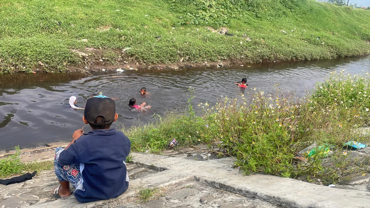 Sungai Cikijing Menghitam: Ancaman Limbah Tekstil Bayangi Warga Rancaekek, Pemerintah Kemana? Anak-anak saat berenang di aliran Sungai Cikijing di Kampung Babakan Jawa, Desa Bojongloa, Kecamatan Rancaekek, Kabupaten Bandung kondisinya sangat mengkhawatirkan tercemari oleh limbah tekstil. Foto Agi/Jabar Ekspres/