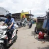 Pengendara motor melintas di samping tumpukan sampah di TPS di Kota Bandung. Foto: Dimas Rachmatsyah / Jabar Ekspres