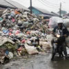 Seorang warga mengendarai motor melintas di samping tumpukan sampah di Pasar Induk Caringin, Kota Bandung, Rabu (16/4). Foto: Dimas Rachmatsyah / Jabar Ekspres