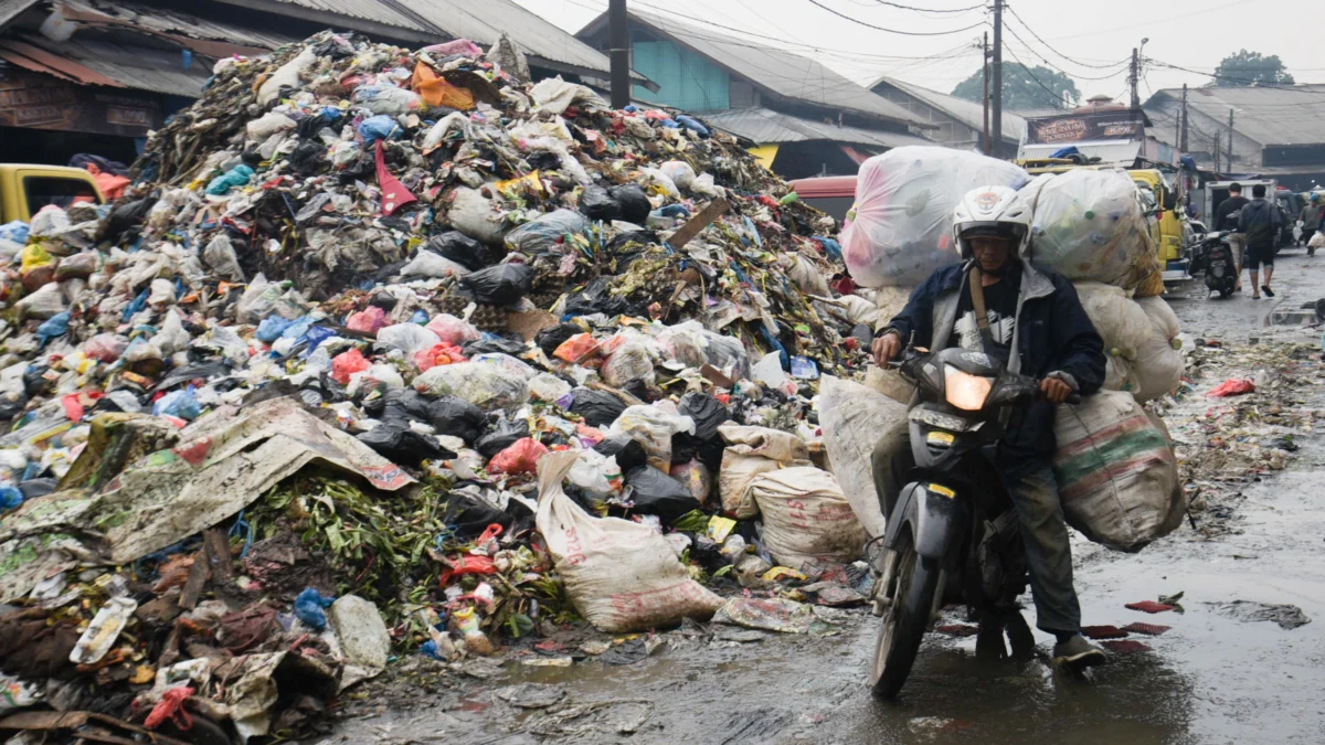 Seorang warga mengendarai motor melintas di samping tumpukan sampah di Pasar Induk Caringin, Kota Bandung, Rabu (16/4). Foto: Dimas Rachmatsyah / Jabar Ekspres