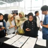 Pencari kerja memindai kode batang pada poster informasi lowongan pekerjaan di salah satu stan perusahaan pada pameran bursa kerja (job fair) di Universitas Kristen Maranatha, Kota Bandung, Kamis (8/5). Foto: Dimas Rachmatsyah / Jabar Ekspres