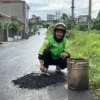 Hasan Fiidel (24), seorang pengemudi ojek online (ojol) di Desa Cibodas, Kecamatan Pasirjambu, Kabupaten Bandung, yang viral di media sosial lantaran menambal jalan berlubang secara pribadi. Foto Agi