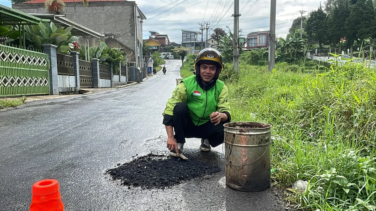 Hasan Fiidel (24), seorang pengemudi ojek online (ojol) di Desa Cibodas, Kecamatan Pasirjambu, Kabupaten Bandung, yang viral di media sosial lantaran menambal jalan berlubang secara pribadi. Foto Agi