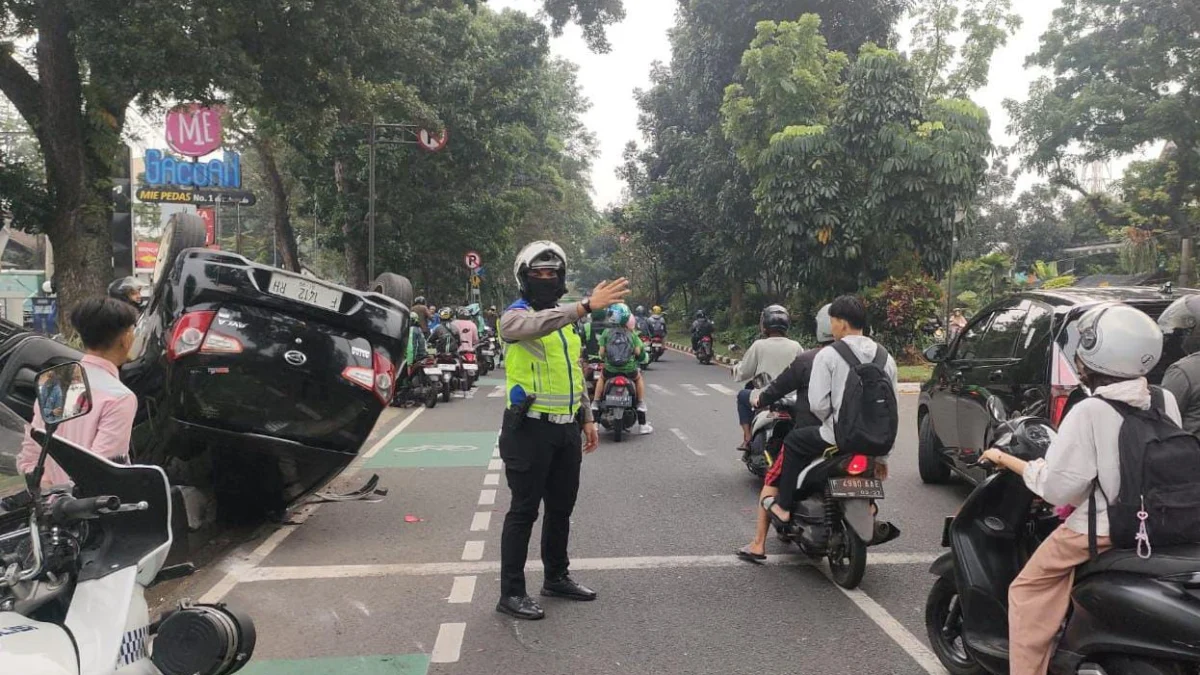 Taksi Online Terguling di Jalan Pajajaran Bogor, Satu Penumpang Luka-Luka Anggota Satlantas Polresta Bogor Kota saat mengatur arus lalu lintas di lokasi kejadian kecelakaan yang melibatkan taksi online di Jalan Raya Pajajaran, Rabu (21/5). (Yudha Prananda / Jabar Ekspres)